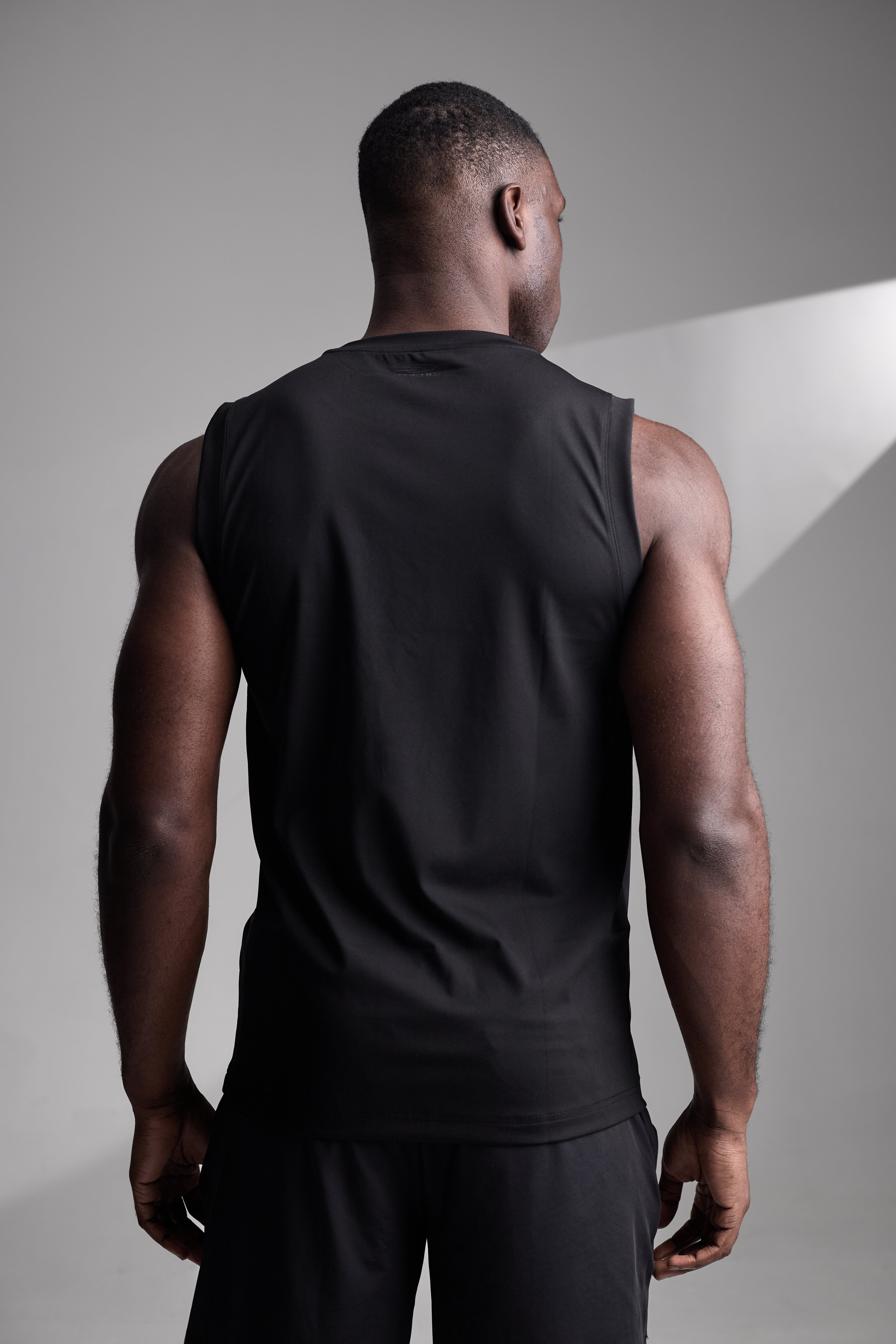 Man wearing a black sleeveless shirt against a gray background