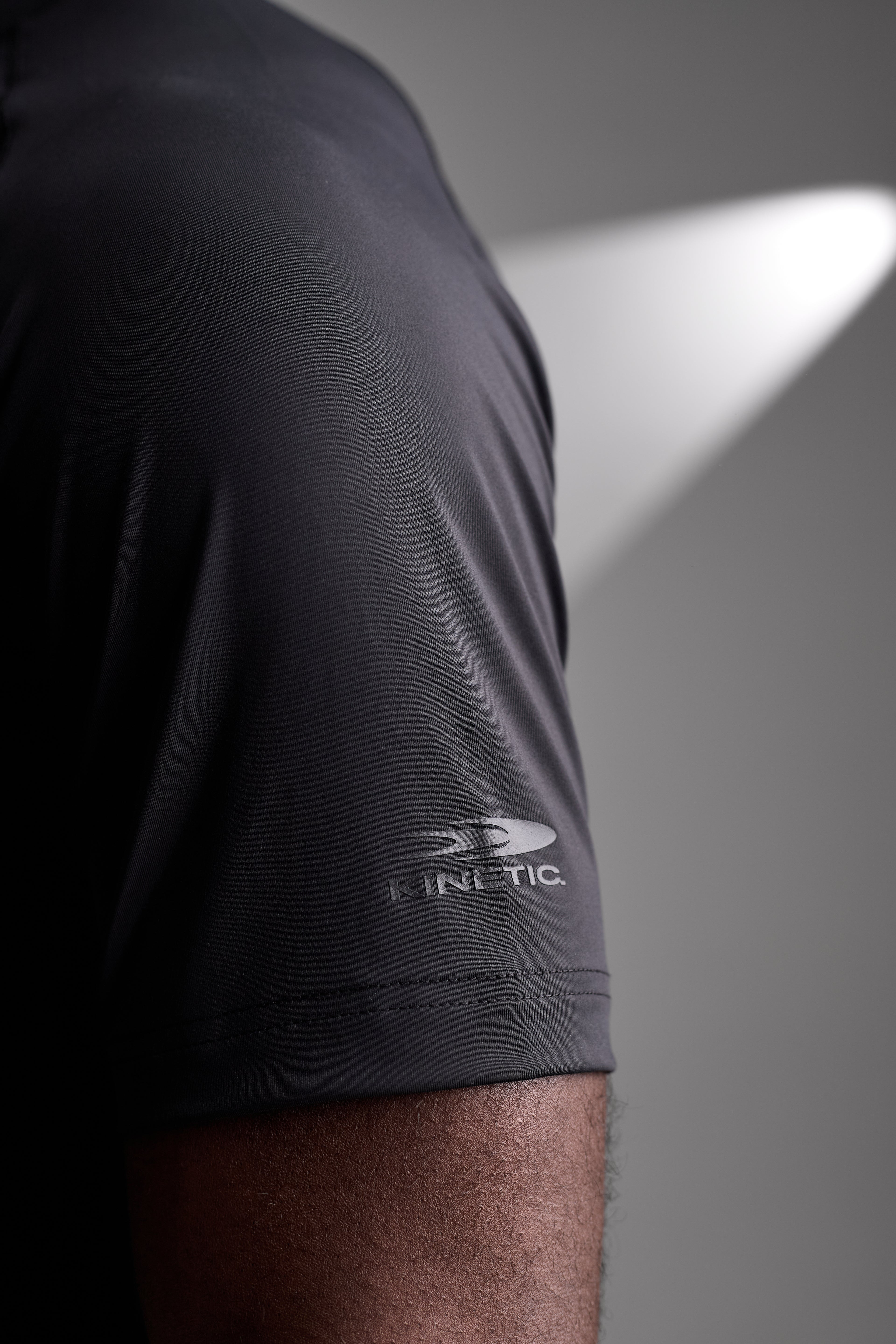 Black athletic shirt with 'Kinetic' logo on a gray background