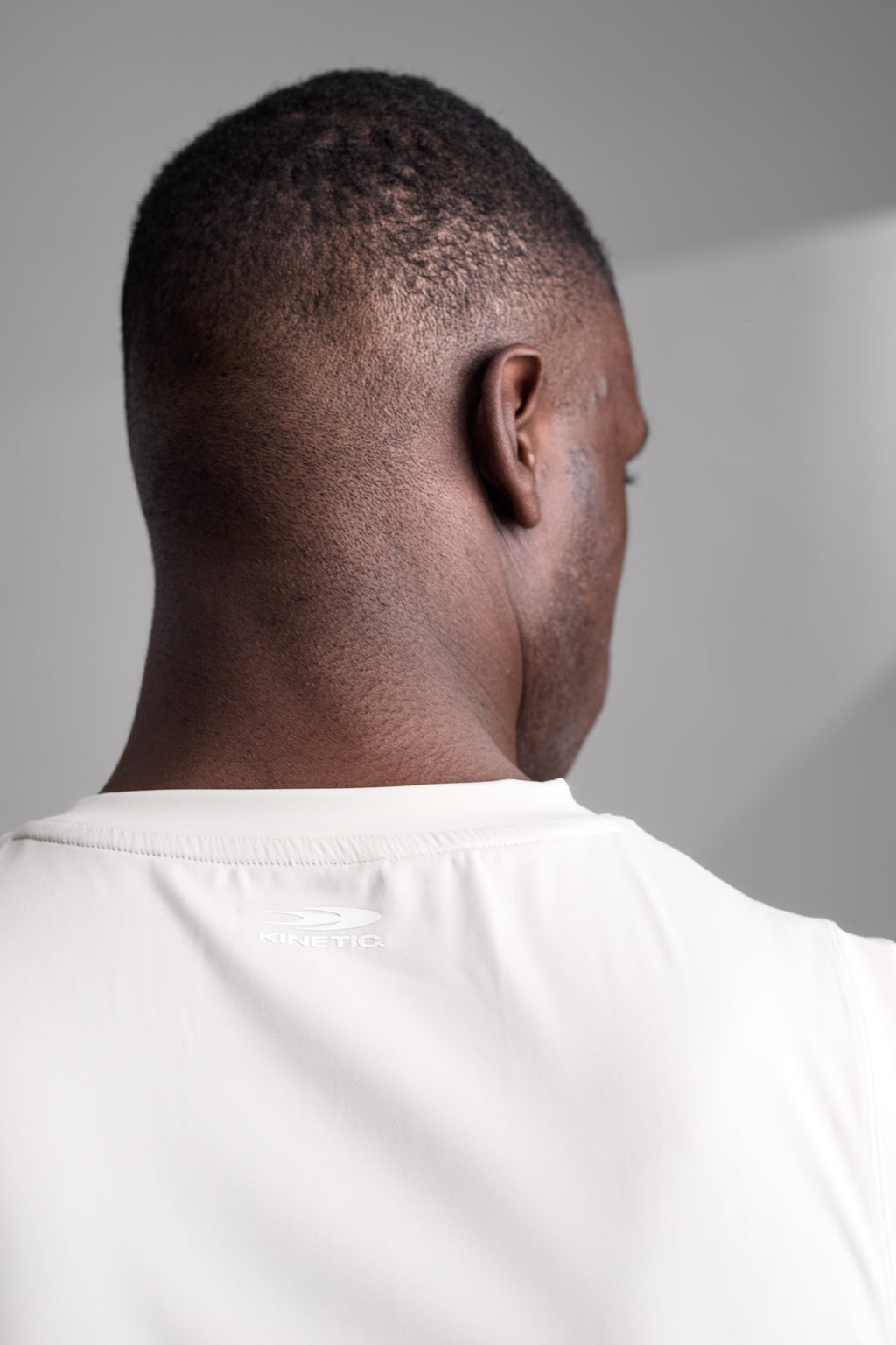 Back view of a person wearing a white athletic white shirt against a gray background