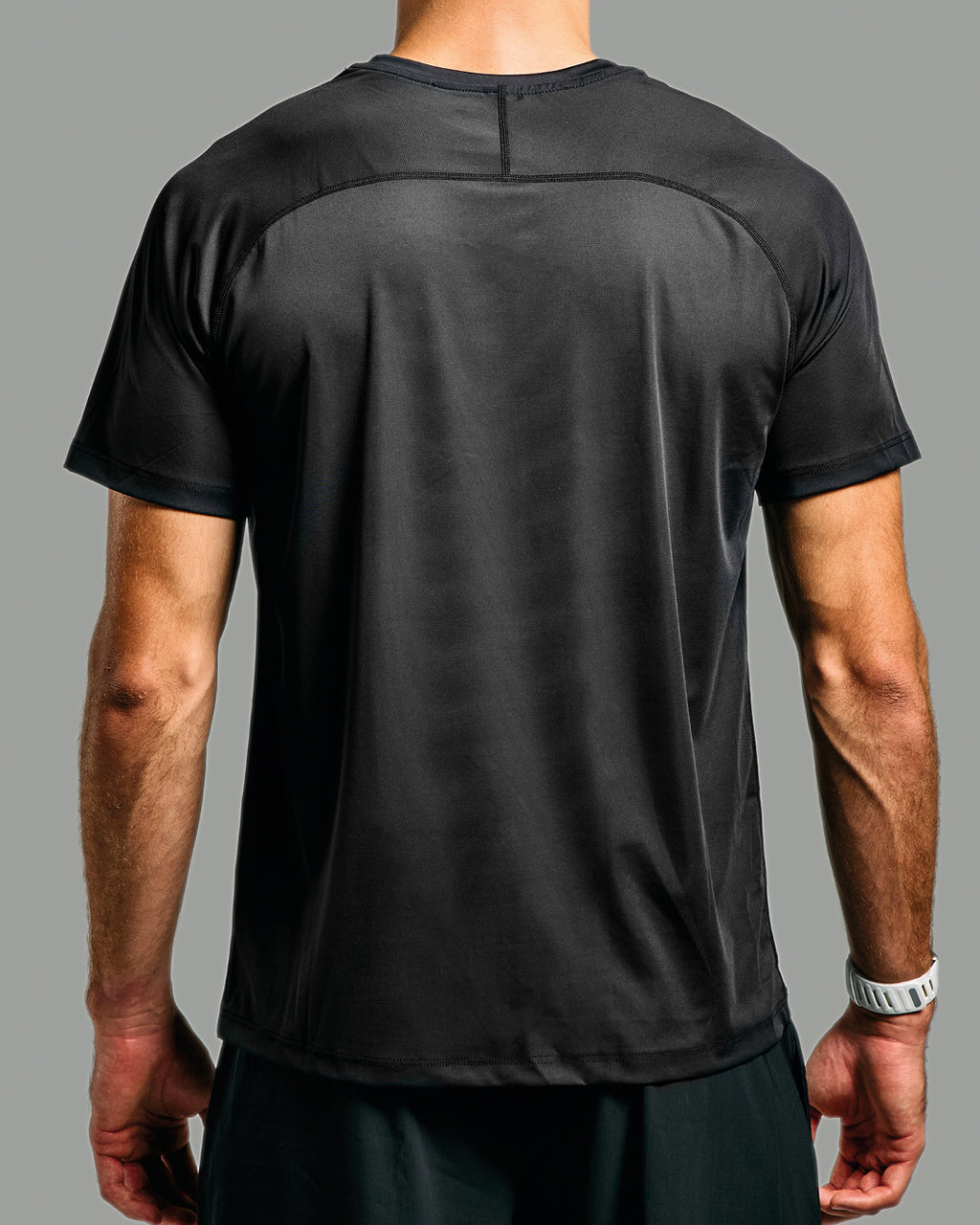 Black athletic shirt worn by a person on a gray background