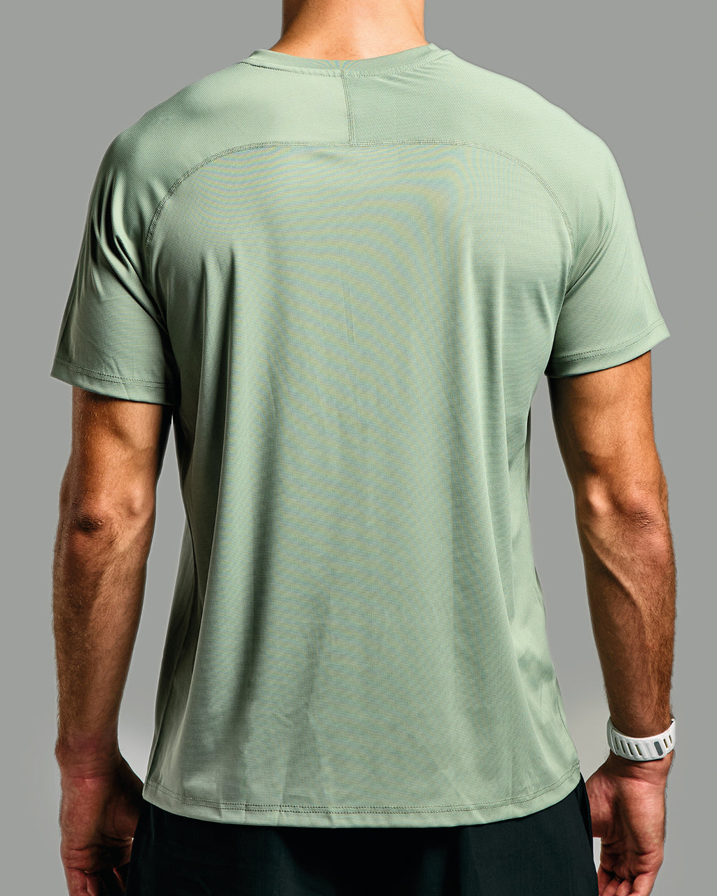 Green athletic shirt worn by a person on a gray background