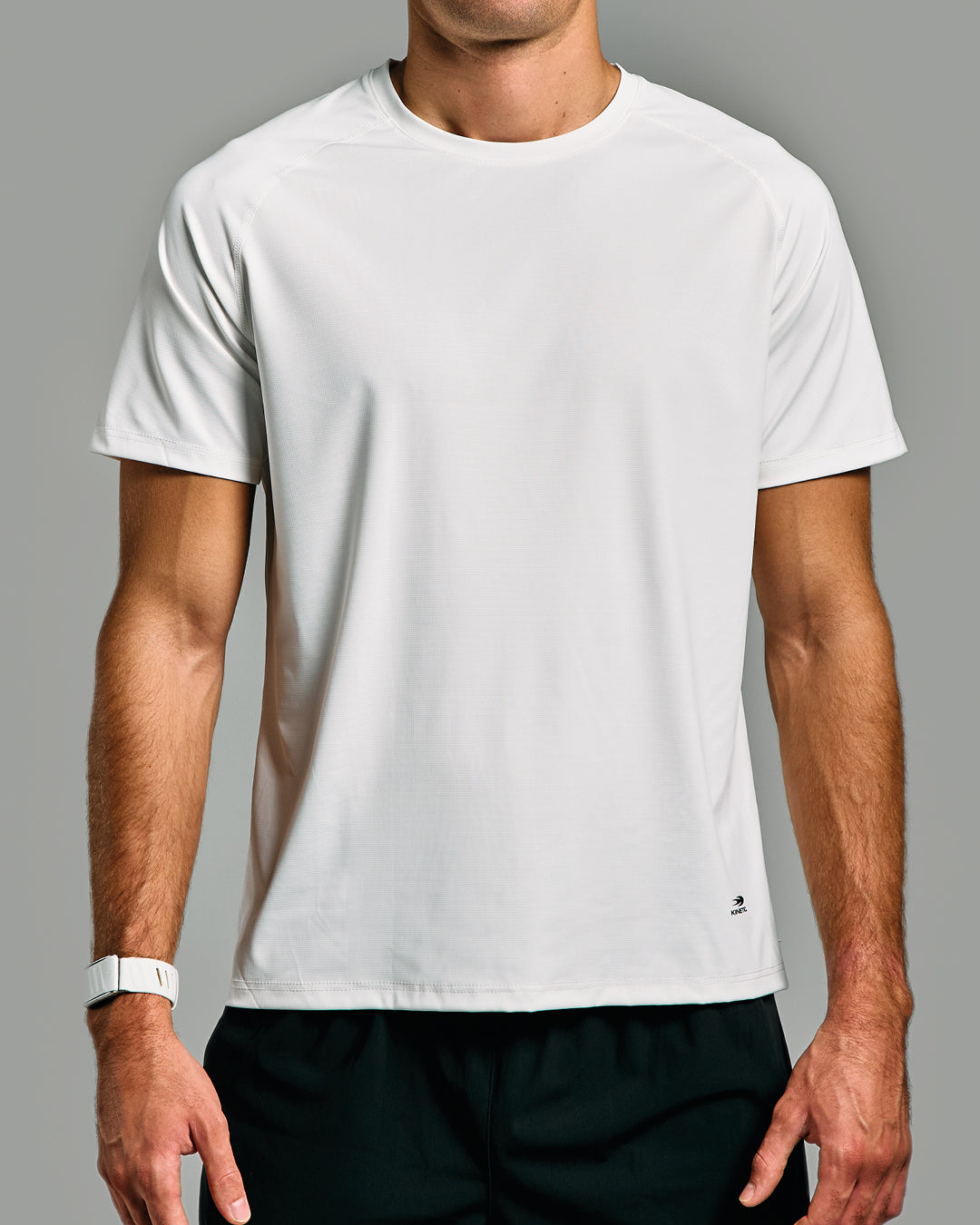 Person wearing a plain white t-shirt against a gray background