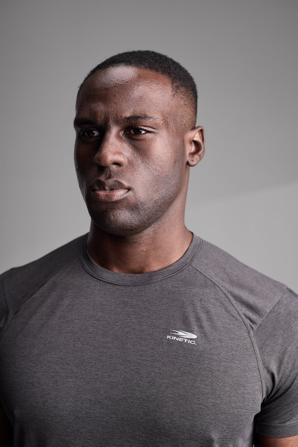 Man wearing a gray fitness t-shirt with a logo on a gray background