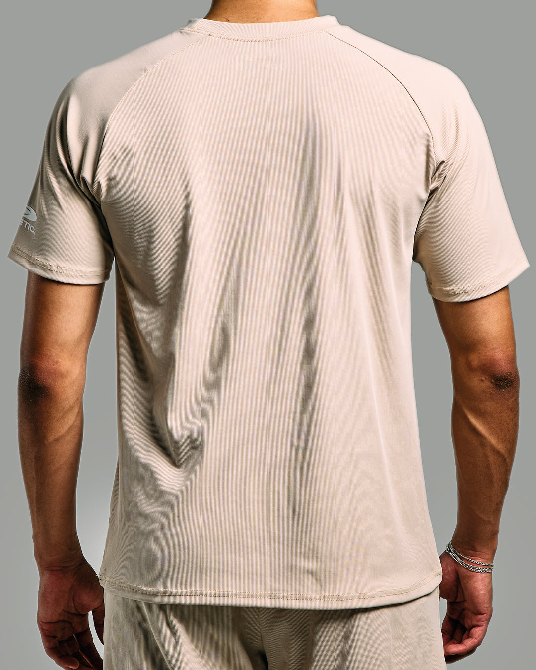 Beige t-shirt worn by a person on a gray background